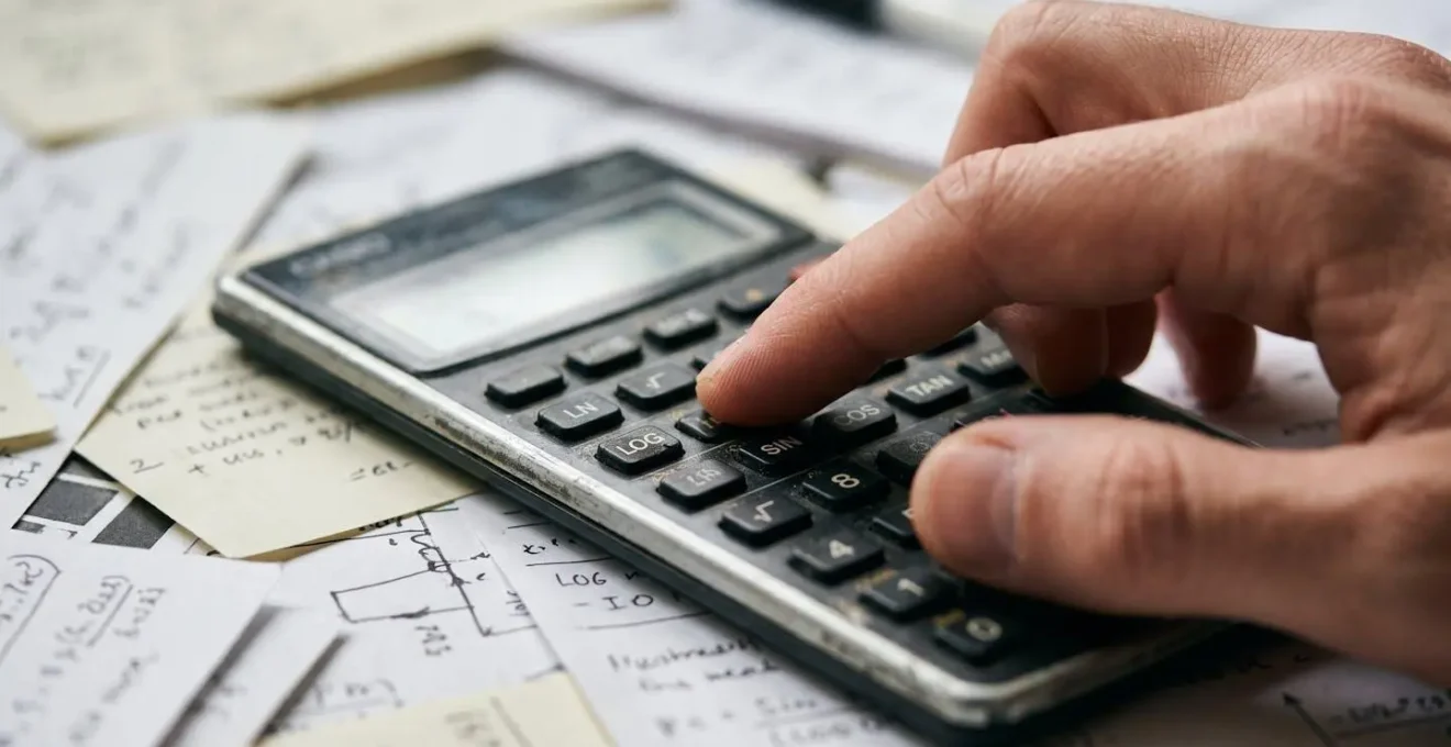 Hands working with calculator and financial documents on desk